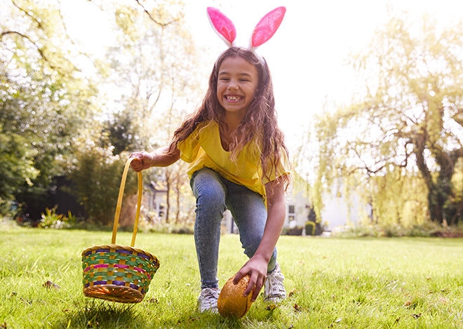 Happy child picking up an easter egg during easter egg hunt