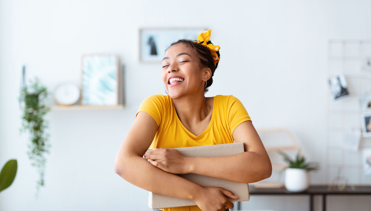 Portrait of smiling female buyer hugging carton cardboard box with a present.