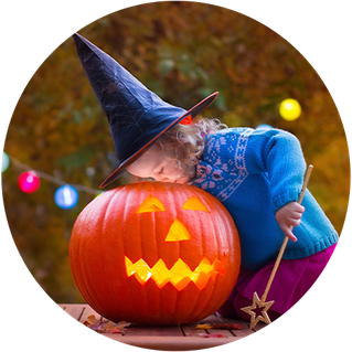 Little girl looking in pumpkin with witch hat