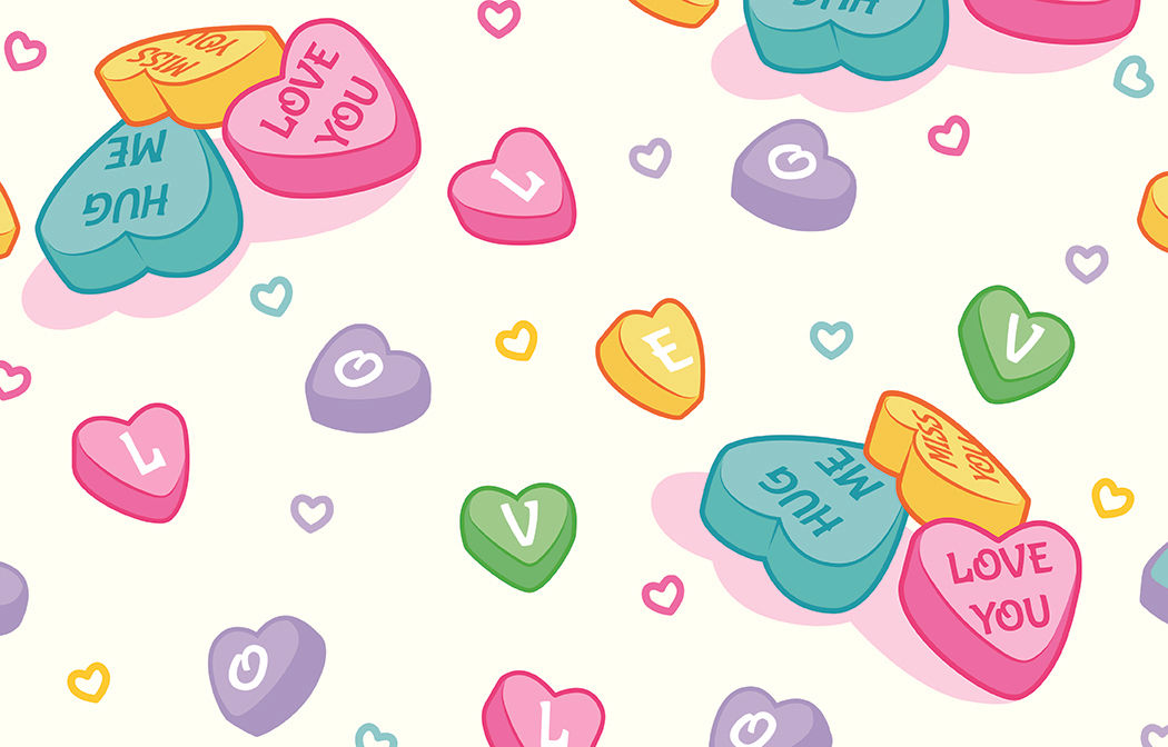 Colorful candy hearts with messages like 'Love You' and 'Hug Me' scattered on a light background with small heart accents