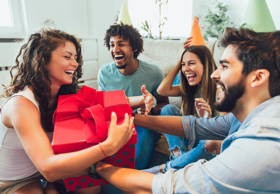 Group of smiling friends celebrating a birthday with gifts